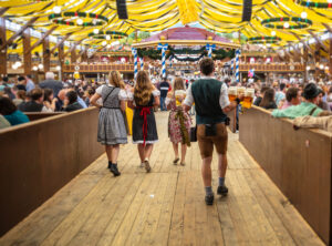 Zeltfest - Kirmes. Vier Personen in Tracht betreten ein Festzelt.