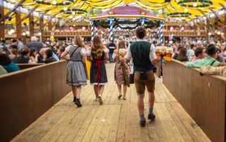 Zeltfest - Kirmes. Vier Personen in Tracht betreten ein Festzelt.